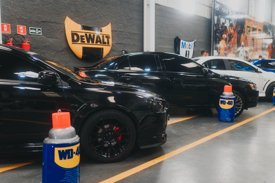 Stylish black sports cars parked in an indoor garage with WD-40 and Dewalt signage visible.