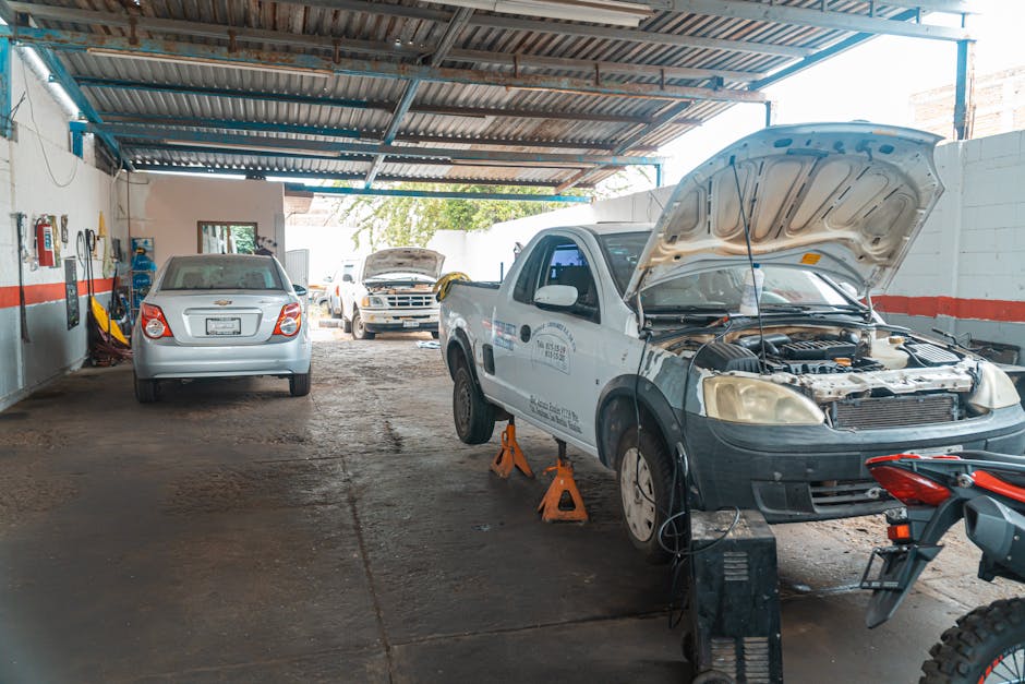 Indoor car repair garage with multiple vehicles under maintenance, showcasing a bustling automotive environment.