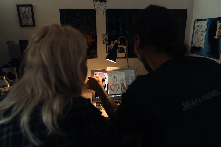 Two adults collaborating on design work in a dimly lit office setting.