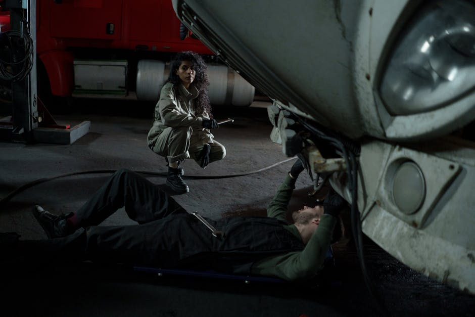 Two mechanics performing maintenance on a truck inside a garage setting.