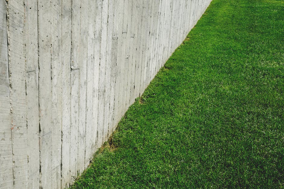 A minimalist outdoor scene featuring a wooden fence alongside a lush green lawn.