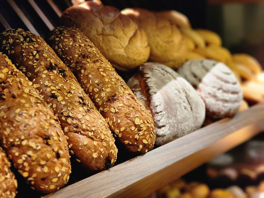 A close-up shot of assorted freshly baked artisan breads in a bakery display.