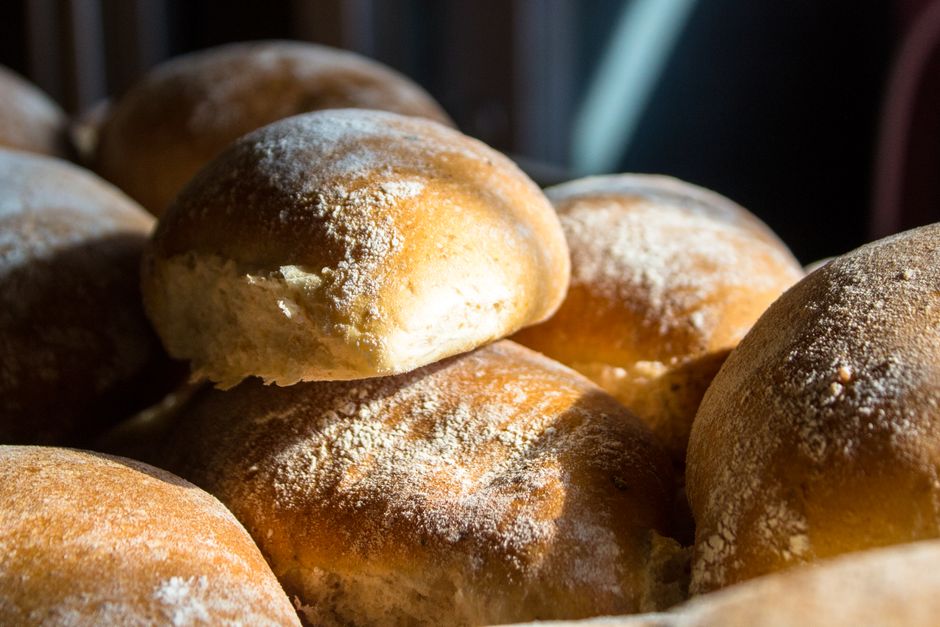 Golden brown bread rolls illuminated by sunlight, showcasing freshly baked texture.