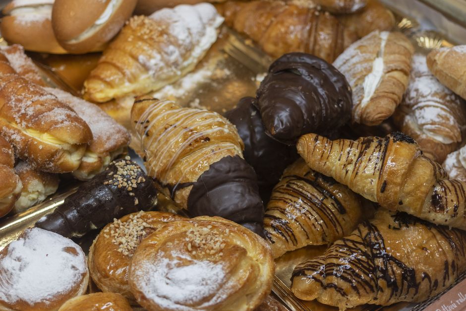 An assortment of fresh croissants and sweet pastries on a tray, perfect for breakfast or a snack.