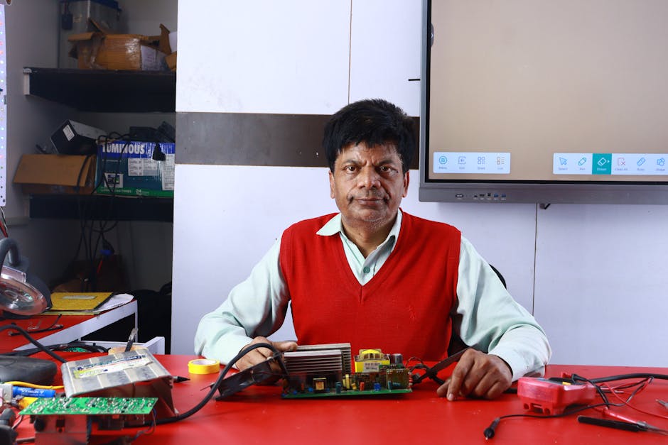 Adult male teaching electronics repair at a training institute, surrounded by circuits.