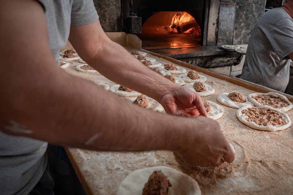 A baker skillfully prepares meat-stuffed dough near a wood-fired oven. Culinary artistry in action.