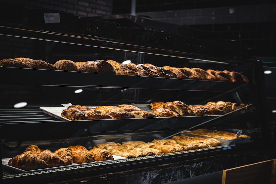 A variety of freshly baked pastries and breads in a glass display case at a bakery.