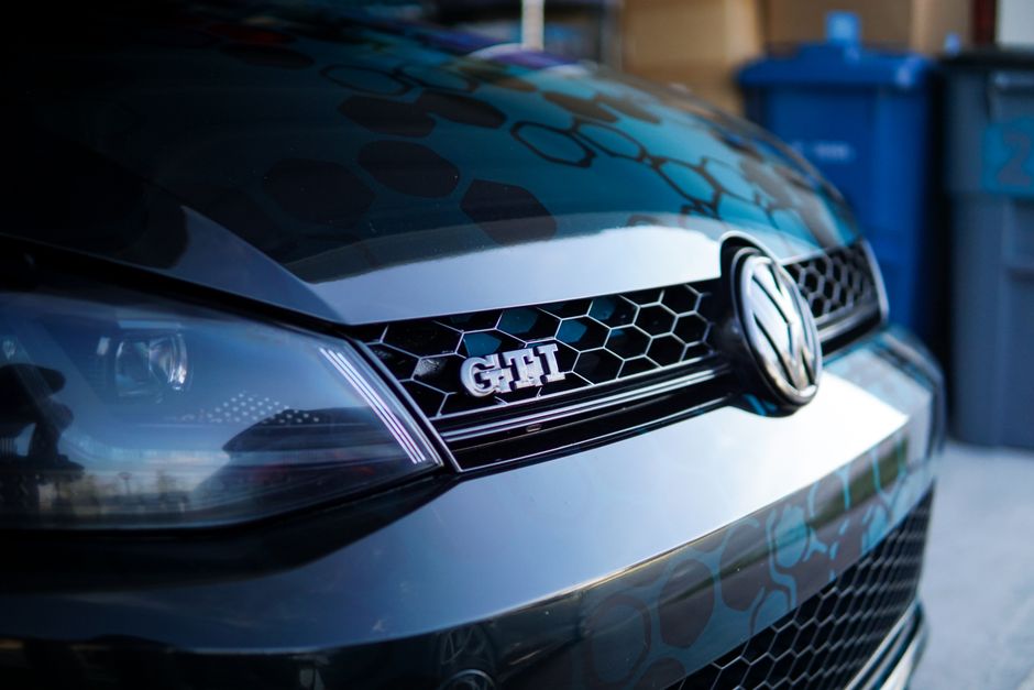 High-quality close-up of a Volkswagen GTI grille showcasing chrome details and branding.