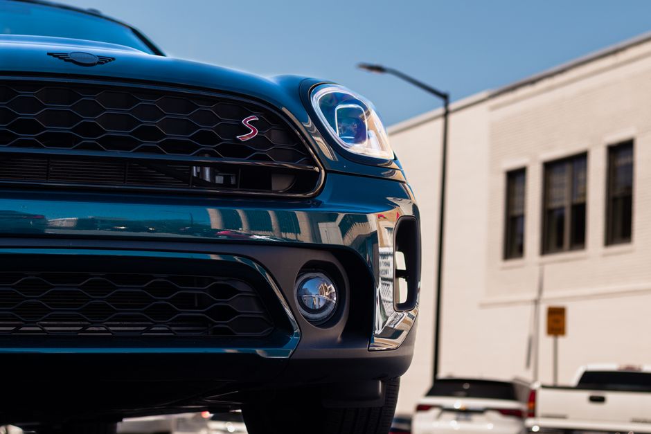 Detailed close-up of Mini Cooper's front grille and headlight in an urban setting.
