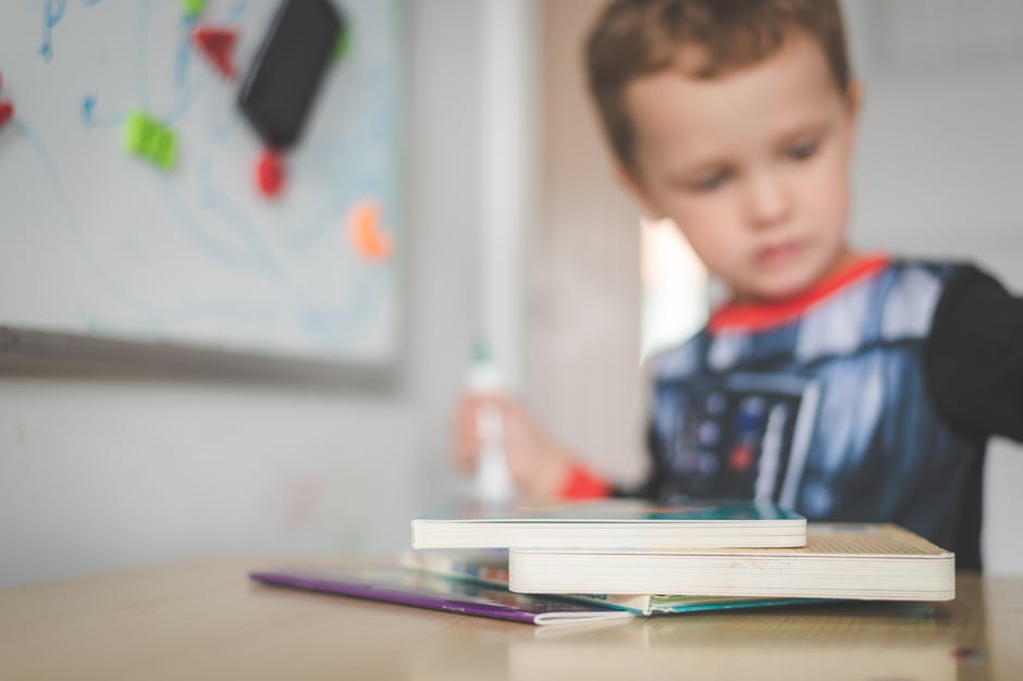 Young boy focused on books at school desk, engaging in learning.