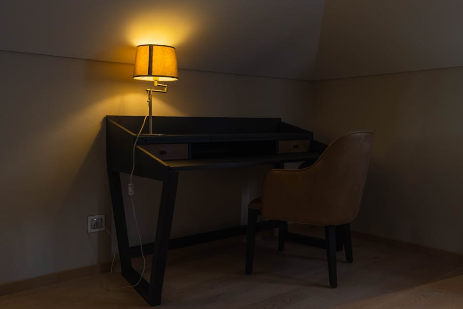 A warm, inviting corner workspace featuring a desk, chair, and lamp.
