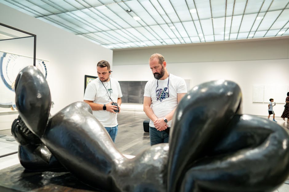 Two men observe a modern sculpture in a gallery setting, showcasing art appreciation.