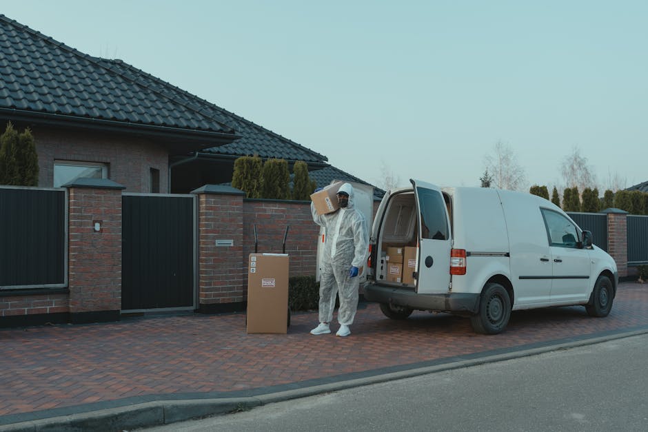 A courier in protective gear delivers packages from a van to a residential house.