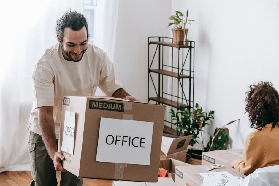 A joyful couple packing boxes labeled 'office' in their home, preparing to move.