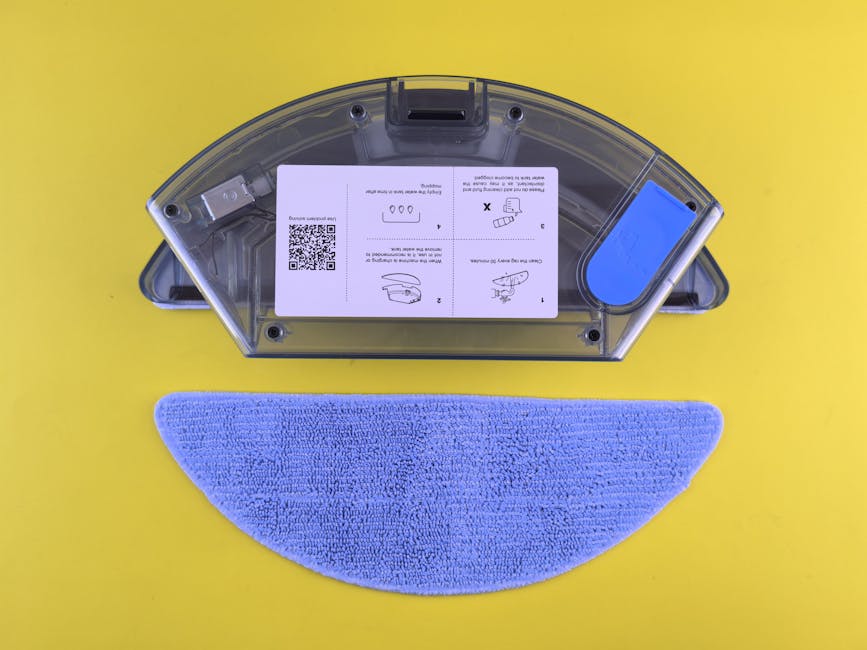 Cleaning robot water tank and mop on yellow backdrop, showcasing household appliance detail.
